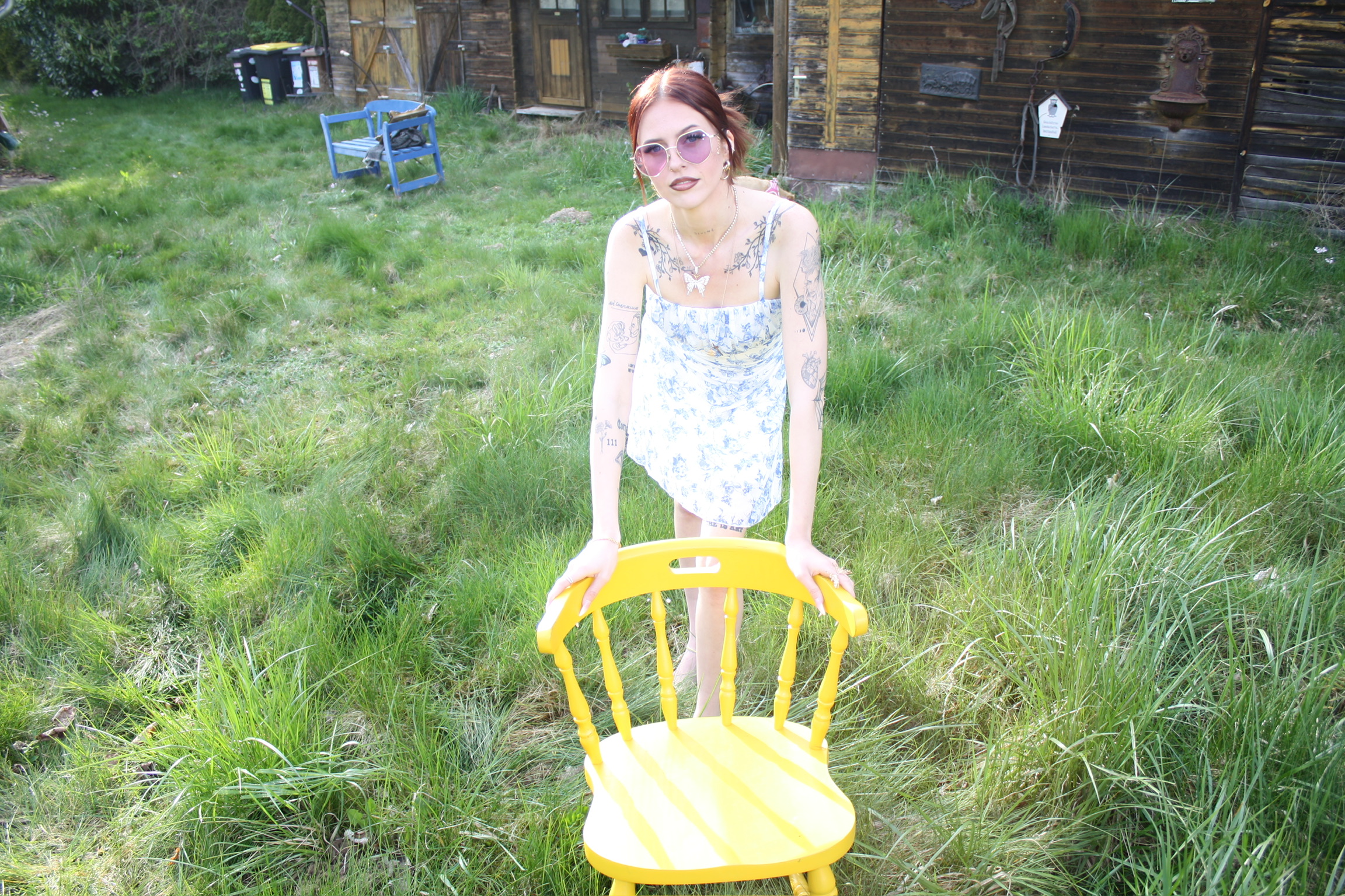Jess holding a yellow chair in a wild garden.
